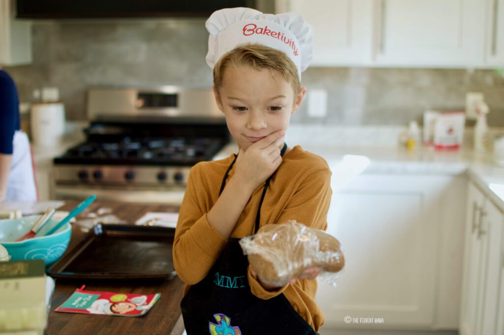 boy with chef hat and apron on holding a dough ball.