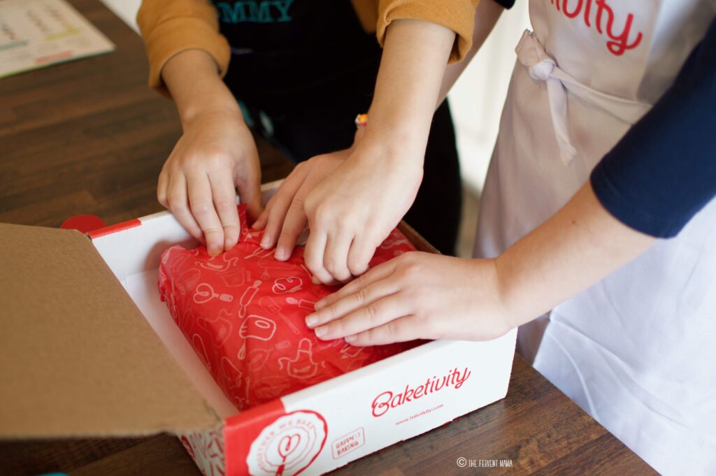 child hands opening the Baketivity subscription baking box for kids.