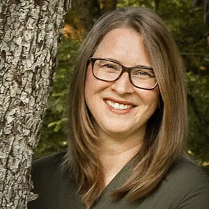 A smiling woman with glasses outdoors near a tree, promoting homeschooling resources and educational support from Homeschool Resource Co.