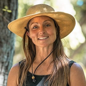 A smiling woman wearing a large straw hat outdoors, perfect for homeschool resource ideas, educational activities, and nature-based learning.