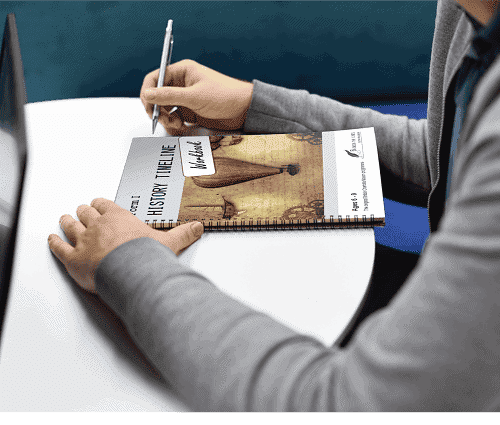 Person writing in a homeschool planner with a pen, sitting at a white table.