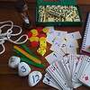 Exif_JPEG_420 Board game setup with dominoes, dice, playing cards, and scorekeeping notes on a wooden table, ideal for family or educational activities.