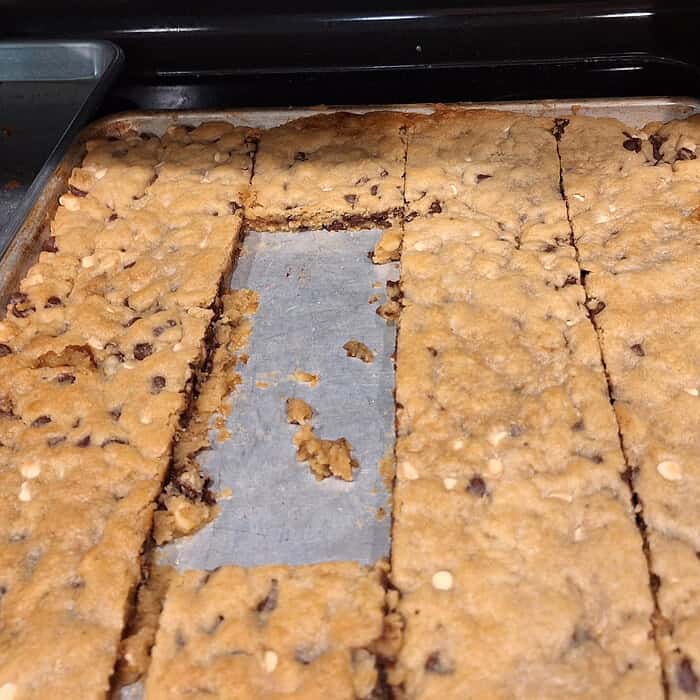 Homemade chocolate chip cookie bars with a missing piece, fresh out of the oven.